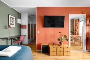 a bedroom with an orange wall with a tv on it at WeHost Spacious Traveller’s HQ Above Metro @Vilhonvuorenkuja 16 in Helsinki