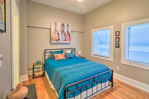 a bedroom with a bed with a blue comforter and two windows at St Louis Apartment Walk to Eating and Entertainment in Tower Grove
