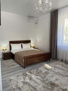 a bedroom with a large bed and a chandelier at Апарт отель Welcome in Taldykorgan