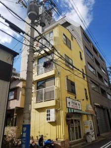 un edificio amarillo al lado de una calle en petit room201三宮10mim en Kobe