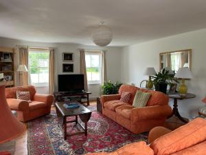 a living room with orange couches and a tv at Ladyurd Farmhouse in West Linton