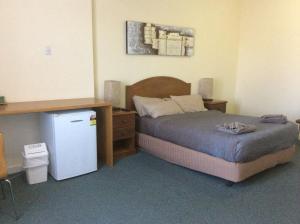 a bedroom with a bed and a small refrigerator at New Whyalla Hotel in Whyalla