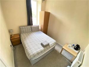 Dormitorio pequeño con cama y mesa en IBROX GuestHouse en Glasgow