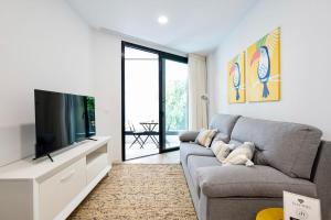 un soggiorno con divano grigio e TV a schermo piatto di Famara Suites by AirNest a Las Palmas de Gran Canaria