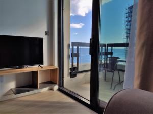 a living room with a tv and a sliding glass door at Silver Beachfront Becici in Becici