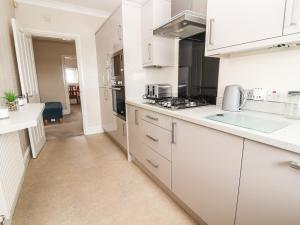 a kitchen with white cabinets and a stove top oven at Ty Uchaf in Rhyl