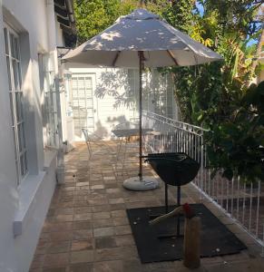 a patio with an umbrella and a table and a grill at 4 Duke Street Flat#2 in Mossel Bay