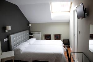 a bedroom with two white beds and a window at Hotel Boutique Rosal Oviedo in Oviedo