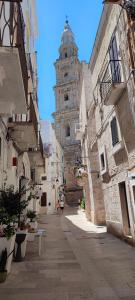 an alley with a building with a clock tower at Lithos house pt 1p e 2p in Monopoli