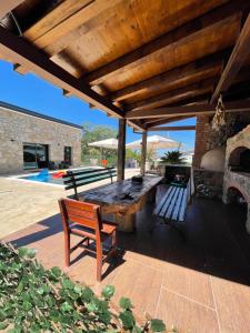 a patio with a wooden table and bench under a roof at Apartman Sara in Bar