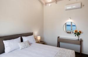 a white bedroom with a bed and a mirror at Nikolaos Apartment in Nydri