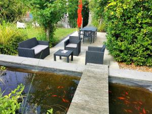 un patio avec des chaises et un étang avec un koi dans l'établissement Archipel Holiday Cottage, à Ellezelles