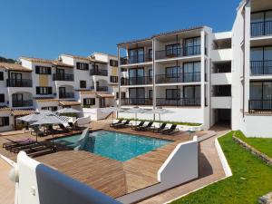 an apartment with a swimming pool and patio furniture at Calallonga Hotel Menorca in Mahón
