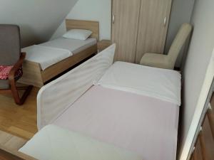 Habitación pequeña con 2 camas y silla en Apartman Ana en Mrkopalj