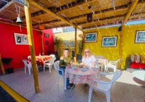 two people sitting at a table in a restaurant at Atenas Backpacker Hospedaje in Paracas