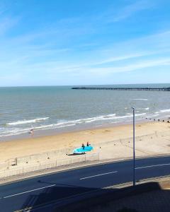 a beach with a person holding a surfboard on the sand at Penthouse Apartment with seaviews in Walton-on-the-Naze