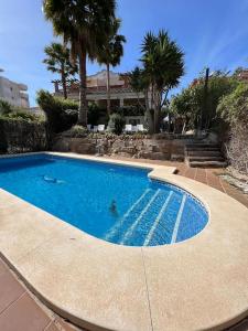 a large swimming pool with palm trees and a building at Casa con piscina en el centro de Marbella. in Marbella