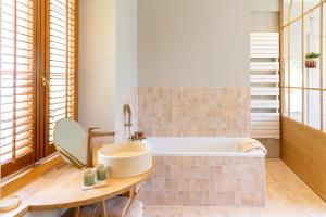 a bathroom with a tub and a table and a sink at CLOS REMY Maison d'hôtes in Précy-sur-Oise