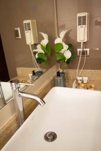 ein Badezimmer mit einem Waschbecken, einem Spiegel und Blumen in der Unterkunft SM Hotel in Lima