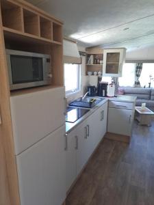 a kitchen with white cabinets and a microwave at De´ Borns Mobielhome in Rheinsberg