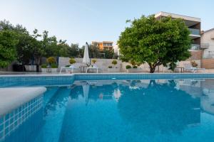 a swimming pool with blue water in front of a building at Sun gardens in Šibenik