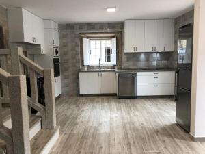 a large kitchen with white cabinets and a sink at Casa A Braña in Arrueiro