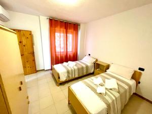 een hotelkamer met 2 bedden en een raam bij APPARTAMENTO LA CALETTA VACANZE in La Caletta