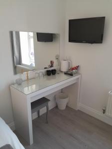 baño con escritorio blanco y TV en la pared en Marques Sands Hotel, en Bournemouth