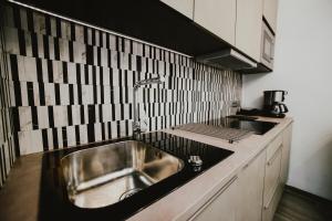 a kitchen with a stainless steel sink and black and white tiles at Kenti Residence in Ljubljana