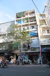 a tall building with a tree in front of a street at Stay&Chill - S.1: Ancient studio nearby Bui Vien in Ho Chi Minh City