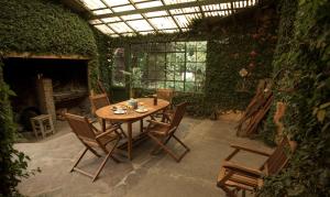 a wooden table and chairs in a room with a greenhouse at Posada Los Mimbres in Gaiman