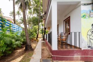 een huis met een palmboom naast een veranda bij Casa De Mor Villa with Pool in Anjuna