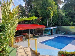 a house with a swimming pool with a red roof at Restaurante y cabinas Sudy in Carara