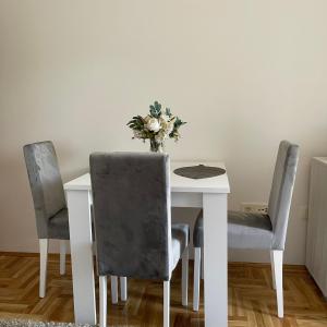 a white table with two chairs and a vase of flowers at Zora Apartment in Plužine