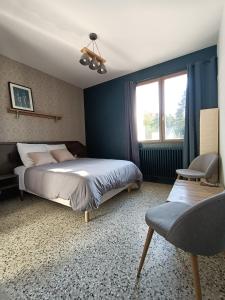 Un dormitorio con una cama y una silla y una ventana. en Les Bois de Malaguet - gite d'étape et de séjour, en Monlet