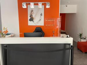 a reception desk in an office with an orange wall at H&ocirc;tel Anna Livia in Cannes