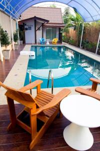 uma piscina com duas cadeiras e uma mesa em Pai Sukhothai Resort SHA Extra Plus em Sukhothai