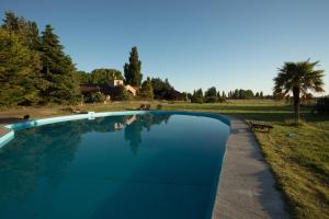 a blue swimming pool with a house in the background at Posada Los Mimbres in Gaiman