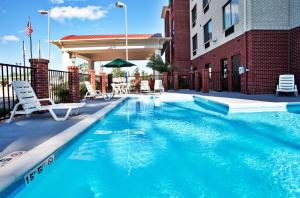 a swimming pool with chairs and a building at Holiday Inn Express Hotel & Suites Biloxi- Ocean Springs by IHG in Ocean Springs