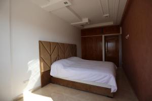een kleine slaapkamer met een bed met witte lakens bij LA PERLE RARE in Agadir