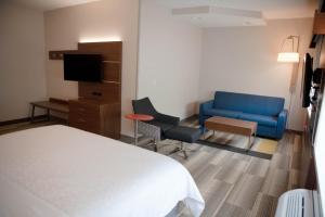 a hotel room with a bed and a blue couch at Holiday Inn Express Winfield - Teays Valley by IHG in Hurricane