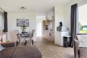 a living room with a table and a kitchen at Landelijk chalet 87 in Oosterwolde