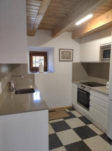 uma cozinha com armários brancos e um piso xadrez em Antigua Casa Chato - tucasaenlospirineos em El Pueyo de Jaca