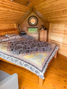 un grande letto in una baita di tronchi con finestra di The Hobbit Hole a Zelah