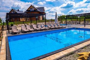 a swimming pool with chairs and a house at Solankowe Zacisze in Baryczka