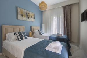two beds in a bedroom with blue walls at Maya apartments Hanioti in Hanioti