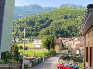 a red car parked on a street with mountains in the background at Apartamento felechosa in Felechosa