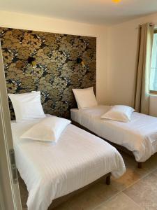 two beds in a room with white sheets and pillows at Gîte Les Muguets - 4 personnes - confort et vue imprenable in Largentière