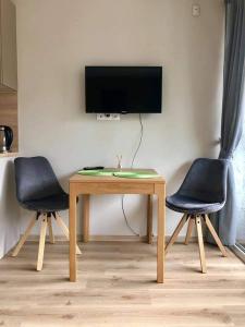 a table with two chairs and a television on a wall at Studija JV36 in Juodkrantė