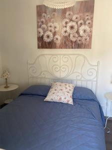 a bedroom with a blue bed with a painting on the wall at Intown - Dammuso in pieno centro storico in Scicli